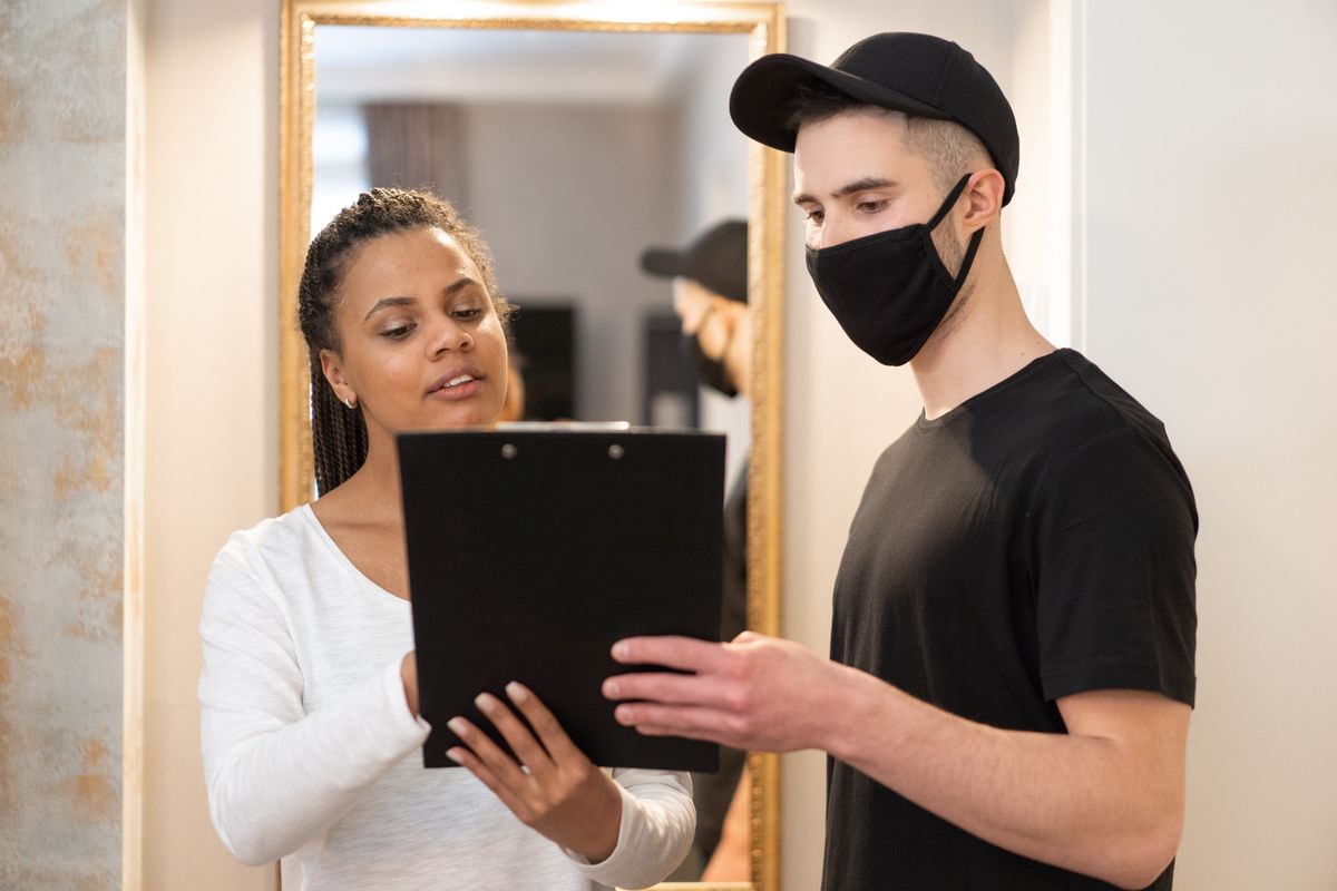 A courier and customer reviewing delivery paperwork together on a clipboard