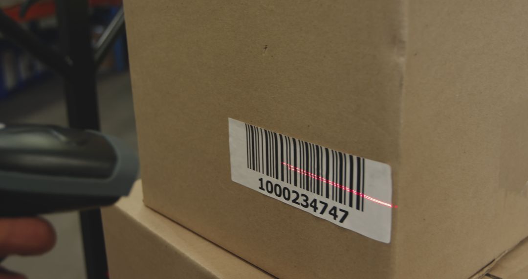 A handheld barcode scanner reading the label on a cardboard parcel